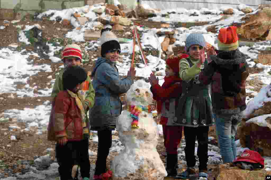Anak-anak pengungsi Suriah bermain dengan salju di sebuah kamp pengungsi di Lembah Bekaa, Lebanon.