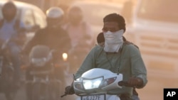 FILE -A man cover his face to protect from the dust in Ahmedabad, India, Wednesday, Feb. 5, 2025. (AP Photo/Ajit Solanki)