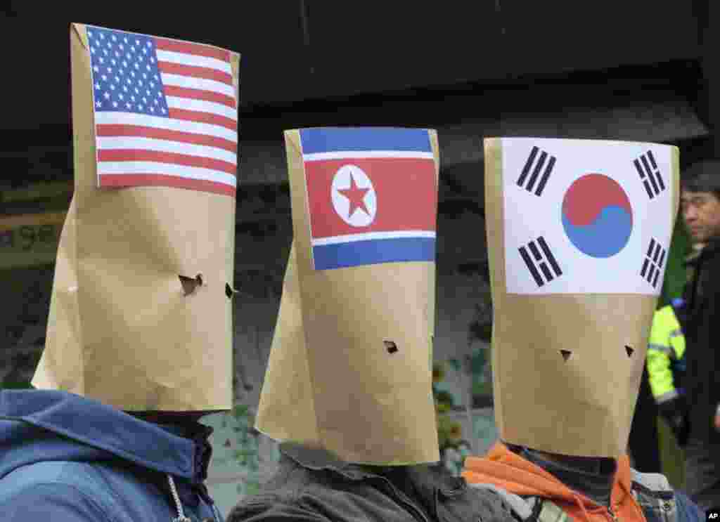 Para demonstran Korea Selatan mengenakan amplop bergambar bendera AS, Korea Utara, dan Korea Selatan memprotes pengeluaran anggaran untuk belanja militer di dekat Kedutaan Besar AS di Seoul. Para pengunjuk rasa menuntut penyelesaian damai di Semenanjung Korea.