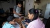 Leidy Martínez lee la tarea de su hijo en su teléfono celular, mientras su otro hijo Joandry, de 12 años, verifica la conexión a internet en una tableta en su casa en el barrio de Las Mayas en Caracas, el jueves 7 de mayo de 2020.