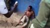 Jean Claude Niyonzima, a suspected member of the ruling party's Imbonerakure youth militia, sits under soldiers' protection from a mob of demonstrators after he came out of hiding in a sewer in the Cibitoke district of Bujumbura, Burundi, May 7, 2015. 
