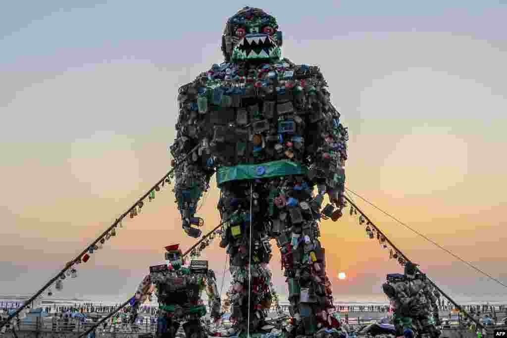 People walk past a giant sculpture of a 'Robot Monster' made of plastic waste to raise awareness about the hazards of polluting the sea, at Cox's Bazar beach, Bangladesh.