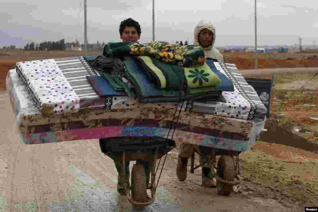 Para pengungsi Suriah memindahkan barang-barang mereka setelah hujan lebat mengguyur kamp pengungsi Al Zaatari di Mafraq, Yordania (12/12).