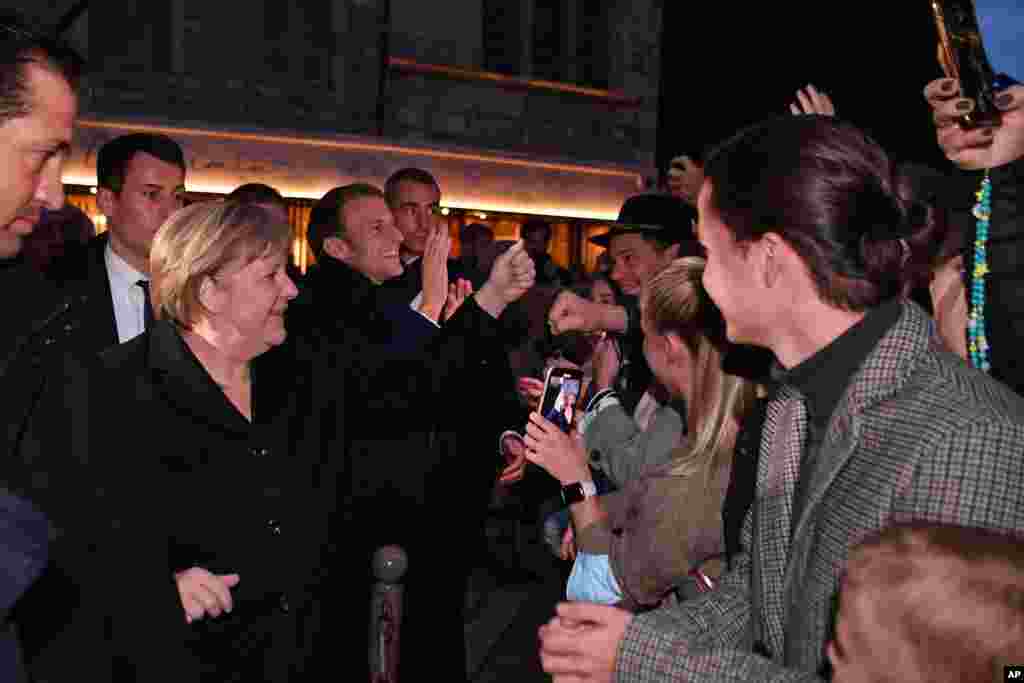 French President Emmanuel Macron, center, and German Chancellor Angela Merkel meet residents in Beaune, Burgundy. Merkel will be feted by France in a special farewell ceremony honoring her leadership and partnership. Merkel is leaving office after 16 years in power. 