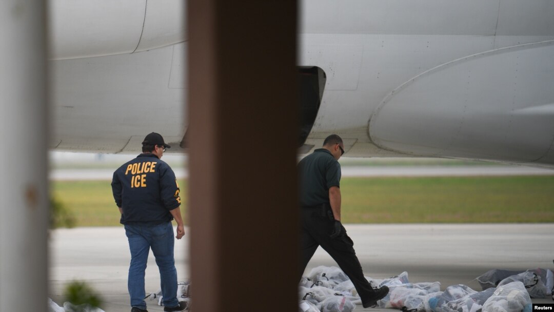 Dos miembros del Servicio de Inmigración y Aduanas de EE. UU. revisan equipajes que subirán a un avión en Brownsville, Texas, el 18 de mayo de 2019.
