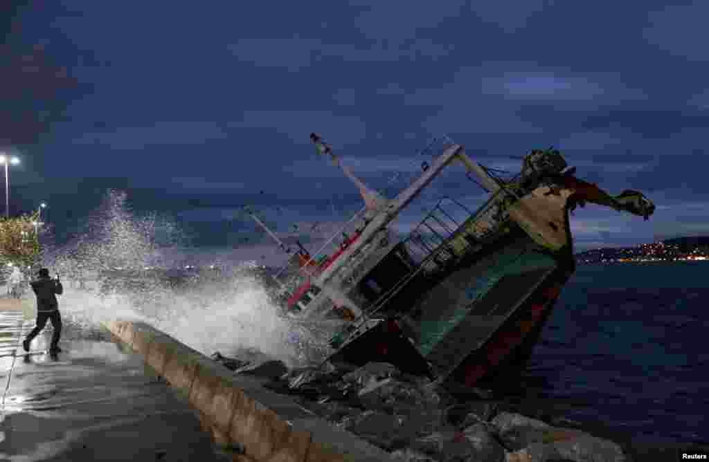A man takes a picture of one of the ships that have been grounded on the shores of the Marmara Sea after extreme winds drove them off their moorings, in Istanbul's Maltepe district, Turkey.