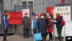 Residents wait to enter a checkpoint with a sign which reads "Returnees to Beijing registration point" in Beijing, China Thursday, Feb. 13, 2020. China is struggling to restart its economy after the annual Lunar New Year holiday was extended to try…