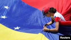 A supporter of Venezuelan opposition leader Juan Guaido, who many nations have recognized as the country's rightful interim ruler, fixes a flag during a rally against Venezuelan President Nicolas Maduro's government in Caracas, Venezuela, April 6, 2019…