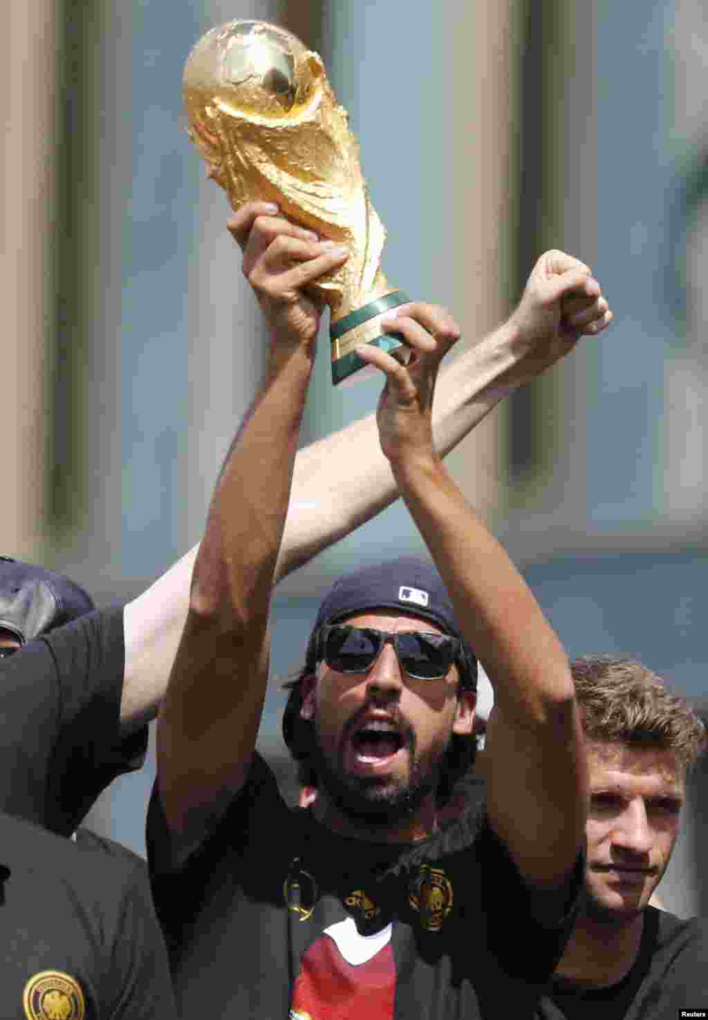 Pemain tim sepakbola nasional Jerman Sami Khedira mengangkat Piala Dunia di panggung dalam perayaan kemenangan mereka di Piala Dunia Brazil 2014, di tempat nobar Fan Mile di Berlin, 15 Juli 2014.