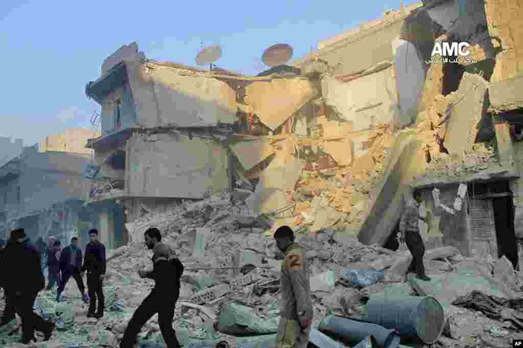 Masyarakat melihat-lihat reruntuhan bangunan yang hancur akibat serangan udara pemerintah Suriah di Aleppo (15/12). (AP/Aleppo Media Center AMC)