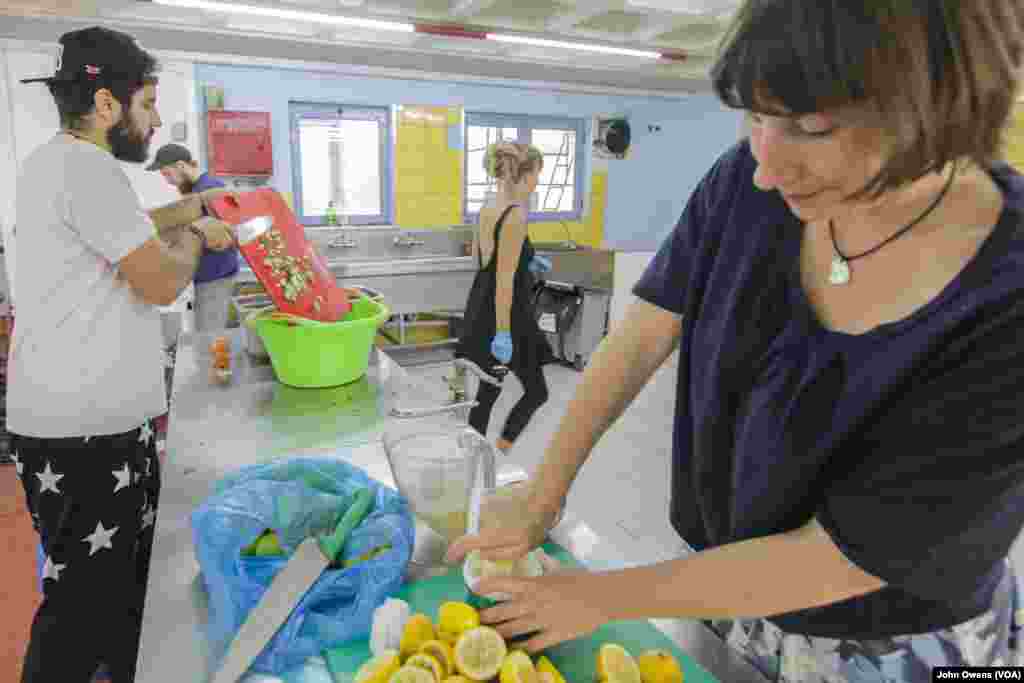 Hassan Mansour dari Suriah (kiri) memasak makanan untuk para pengungsi di pusat komunitas Khora di Athena, Yunani (24/10). Tempat penampungan itu seringkali menyediakan makanan Suriah, sebagai selingan dari menu rutin kentang rebus dan pasta.