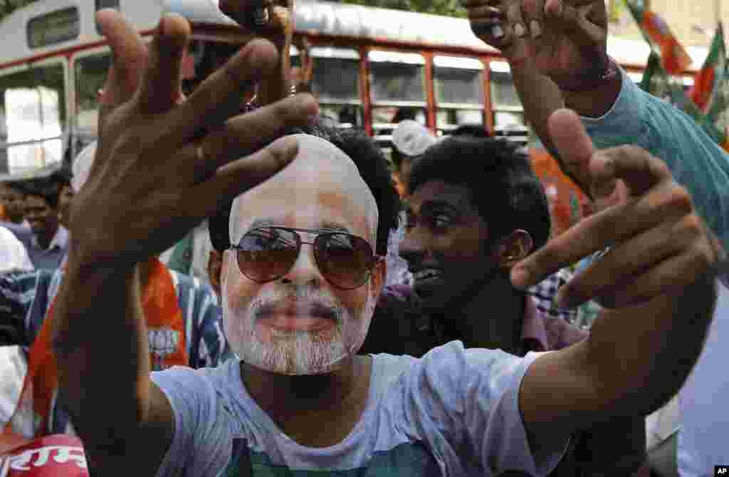 Para pendukung Partai Bharatiya Janata (BJP) memakai topeng Perdana Menteri India yang baru Narendra Modi dalam perayaan sebelum upacara pelantikannya di Mumbai (26/5). (AP/Rajanish Kakade)
