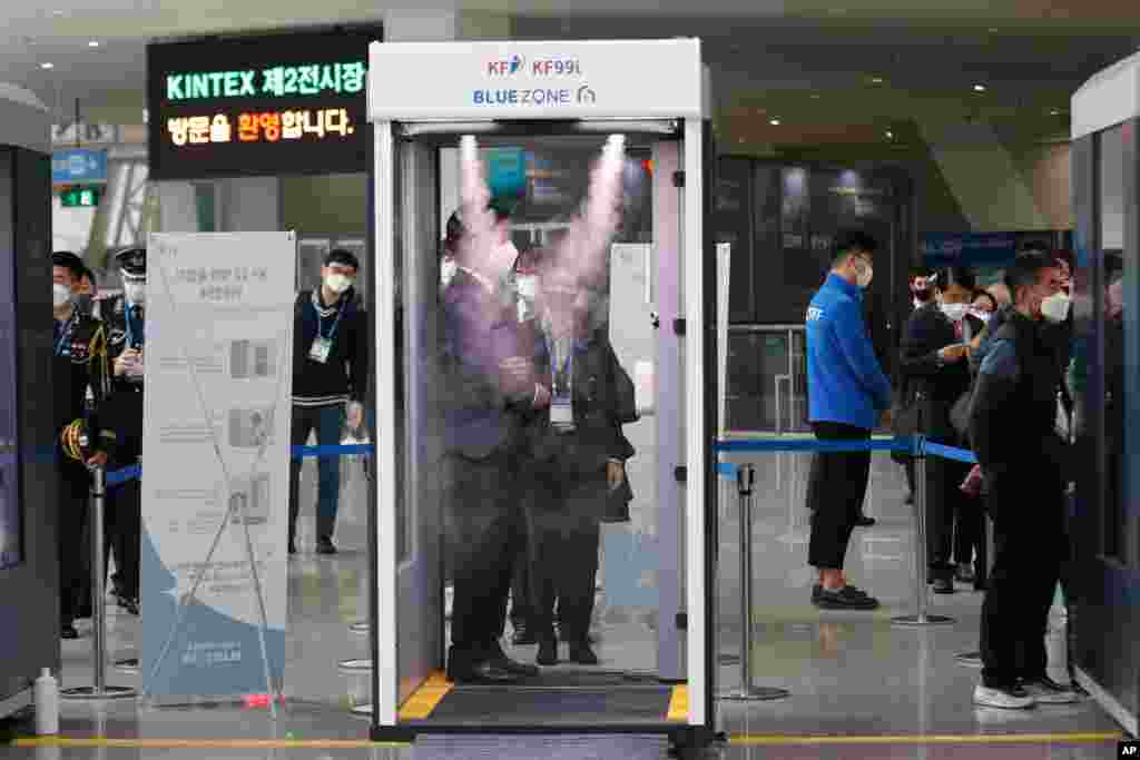 한국 고양시 일산 킨텍스에서 열린 무기 전시회인 '대한민국 방위산업전' 참석자들이 신종 코로나바이러스 방역을 위한 소독 부스를 통과하고 있다. 한국의 일일 신종 코로나바이러스 확진자 수가 3개월만에 또 다시 최다 기록한 가운데 정부는 사회적 거리두기 지침을 강화하고 있다.
