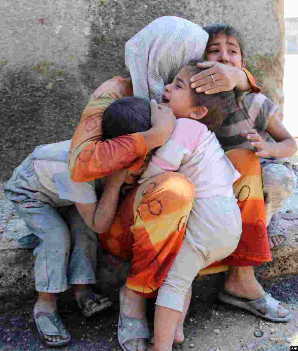 Seorang Ibu menenangkan ke-3 puteranya setelah rumah mereka di kota Aleppo hancur akibat serangan bom dari pasukan Suriah.