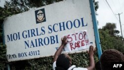 An activist puts a message on the sign board at the main entrance of Moi Girls School Nairobi, a prestigious government boarding school in Nairobi, Kenya, June 4, 2018, during a protest against alleged rape of three girls at the school.