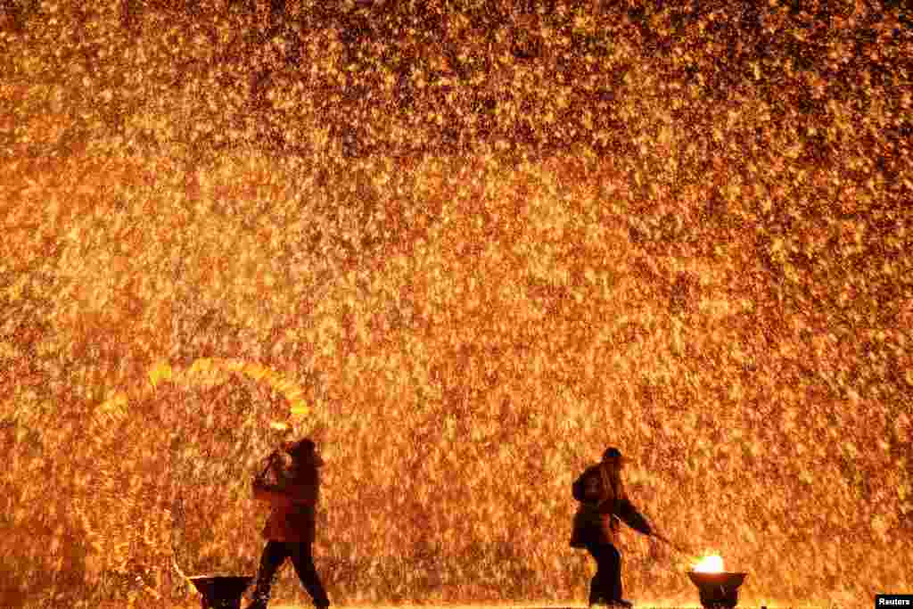 Performers throw molten iron against a wall to create sparks during a traditional performance ahead of the Dragon Boat festival in Zhangjiakou, Hebei province, China, May 29, 2017.