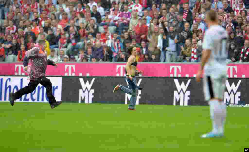 Seorang penggemar sepak bola dikejar petugas keamanan lari ke tengah lapangan dalam pertandingan sepak bola divisi pertama Jerman Bundesliga antara FC Bayern Munich dan FC Freiburg di Munich, Jerman.