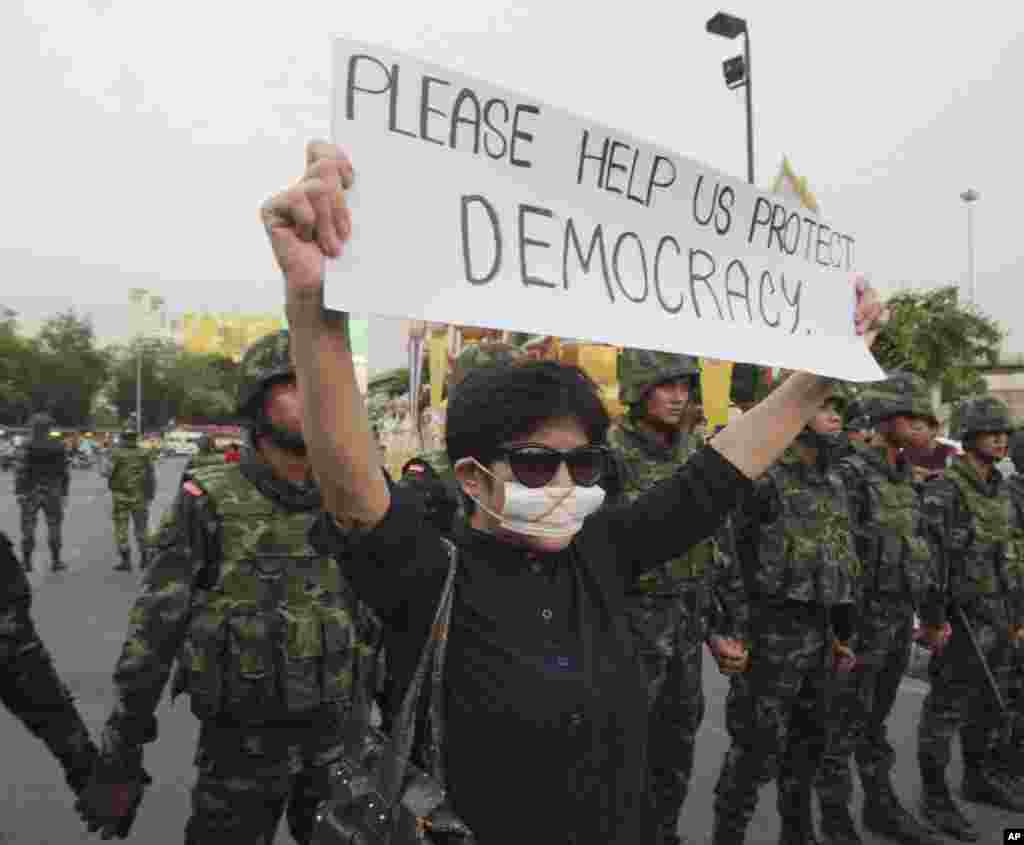 Seorang demonstran membawa kertas bertuliskan "Bantu Kami Lindungi Demokrasi" dalam sebuah protes anti-kudeta di Monumen Kemenangan di Bangkok (26/5). (AP/Sakchai Lalit)