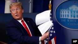 ARCHIVO - El presidente Donald Trump sostiene papeles mientras habla sobre el coronavirus en la sala de conferencias de prensa James Brady de la Casa Blanca, el 20 de abril de 2020 en Washington.