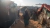 A girl carries a baby boy in a camp in Kismayo, Somalia, that is home to both displaced Somalis and returned refugees on September 27, 2016. (J. Patinkin/VOA)