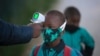 Un agent vérifiée la température d'un garçon en rapport avec pandémie de coronavirus, avant qu'il n'entre dans son école, à Johannesburg, en Afrique du Sud, le 7 juillet 2020.