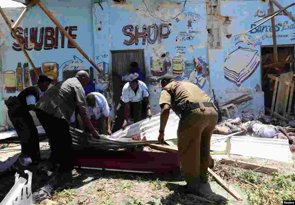 Somali police move a dead body from the scene of a suicide car bomb attack next to a cafe in the suburbs of Mogadishu, Feb. 27, 2014.