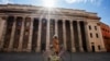 A woman walks in empty Piazza di Pietra square, in Rome, Wednesday, March 18, 2020. For most people, the new coronavirus causes only mild or moderate symptoms. 