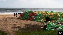 Ljudi hodaju pored hrpe plastike koju je okean izbacio na obalu nakon požara na kontejnerskom teretnjaku MV X-Press Pearl u Kapungodi, u predgrađu Kolumba, Šri Lanka, 11. juna 2021.