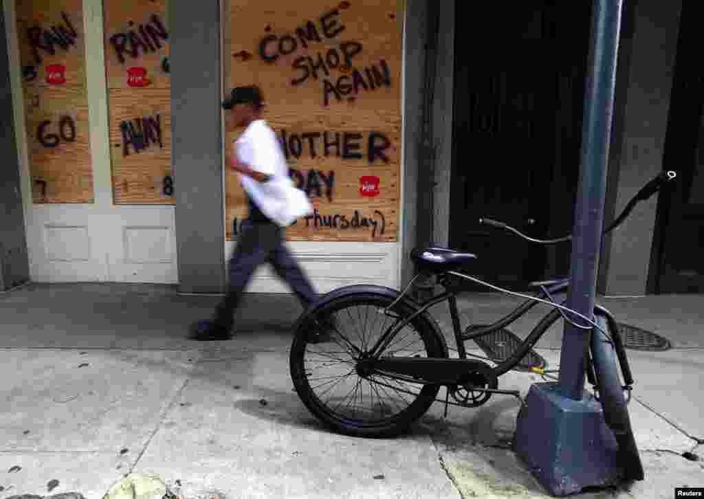 A man walks by a boarded up business in the French Quarter as business owners prepare for tropical storm Isaac in New Orleans, Louisiana August 27, 2012.