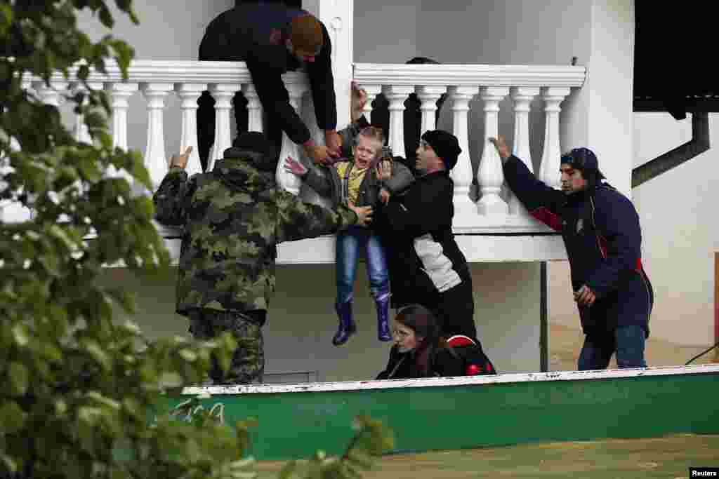 Tentara angkatan darat Serbia mengevakuasi seorang anak laki-laki dari sebuah rumah yang kebanjiran di ktoa Obrenovac, barat daya Belgrad, Serbia (17/5). (Reuters/Marko Djurica)