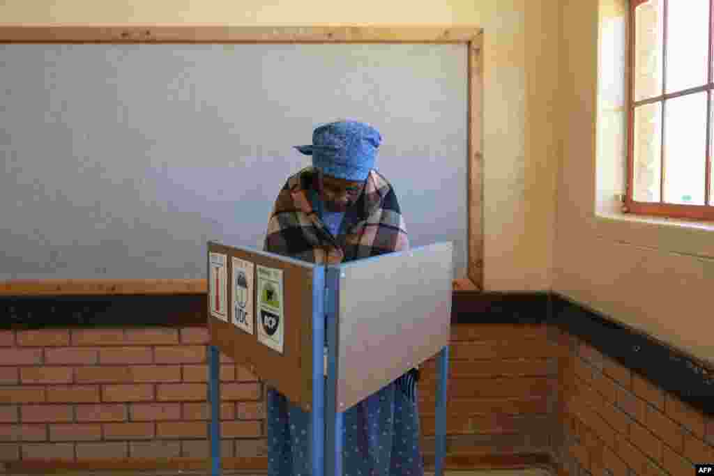 An elderly voter marks her ballot in a voting booth at Mosielele Primary School polling station in Moshupa Village, west of Gaborone, during Botswana's general election.