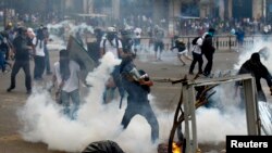 Anti-government protester throws teargas canister back at police during riots at Altamira square, Caracas, March 6, 2014.