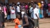 FILE: A man wearing a mask is seen near a food queue in Harare, Zimbabwe, March 25, 2020. 