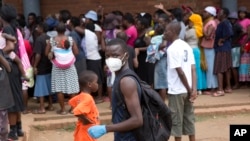 FILE: A man wearing a mask is seen near a food queue in Harare, Zimbabwe, March 25, 2020. 