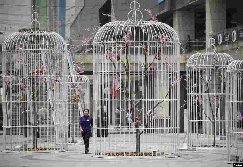 Seorang perempuan berjalan melewati sebuah karya seni 'kandang burung raksasa' yang berisi pohon-pohon buatan dan burung di kota Nanjing, provinsi Jiangsu, China.