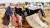 A woman and child sit together in an enclosure made from fabrics at a make-shift camp for displaced Yemenis in the northern Hajjah province, Dec. 16, 2019.