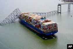 In this aerial image released by the Maryland National Guard, the cargo ship Dali is stuck under part of the structure of the Francis Scott Key Bridge after the ship hit the bridge, Tuesday, March 26, 2024, in Baltimore. (Maryland National Guard via AP)