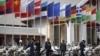 Lao police officials stand next to flags of various nations on display at Wattay International Airport in Vientiane, Laos, Sunday, Nov. 4, 2012.
