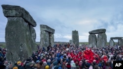 FILE - People celebrate the Winter Solstice sunrise celebrations at Stonehenge, England, Saturday, Dec. 21, 2024. (AP Photo/Anthony Upton)