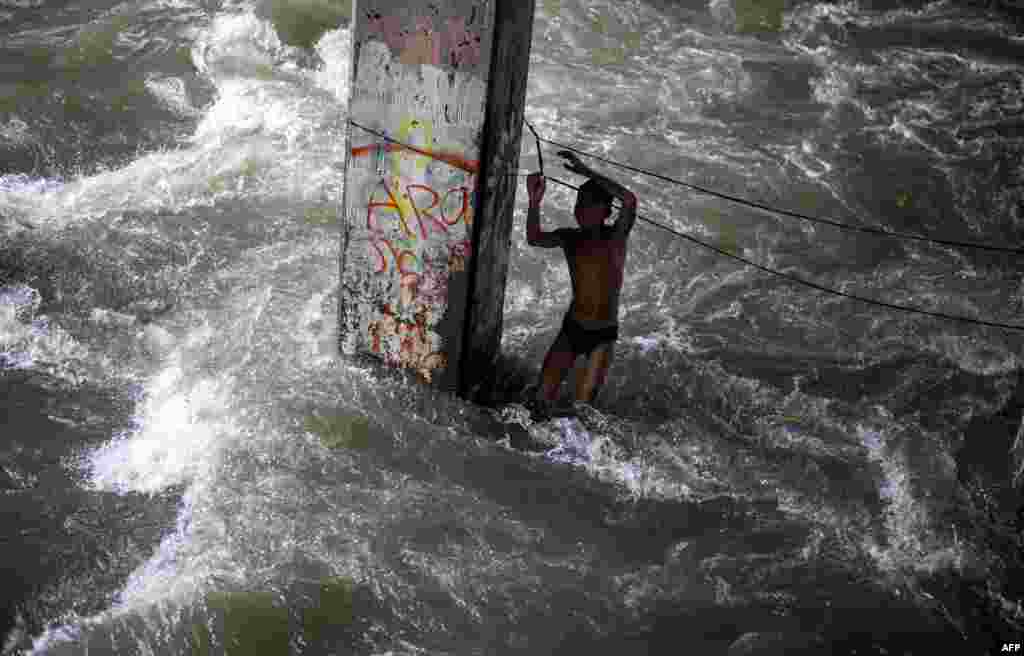 A boy plays in a swollen creek under a bridge in Manila,Philippines. Typhoon Sarika lashed the main Philippine island of Luzon, flattening homes and toppling trees and power pylons as more than 12,000 people fled to safer ground, officials said. Shanties built beside a river, under a creek are the usual victims of floodings. 