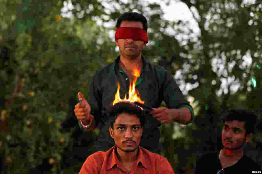 Hair artist Vishnu Limbachiya styles a man's hair while wearing a blindfold at a park in Ahmedabad, India.