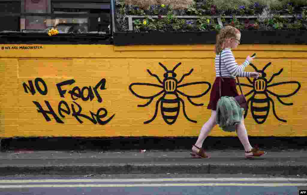 A woman passes a street-art graffiti mural, created following the May 22 terror attack at the Manchester Arena, featuring bees, which are synonymous with Manchester as a symbol of the city's industrial heritage, in Stevenson Square, Manchester.