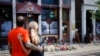 Dos personas observan el martes 6 de agosto, un altar improvisado en memoria de las víctimas de un tiroteo en Dayton, Ohio, ocurrido el domingo 4 de agosto en el Distrito Oregon. 