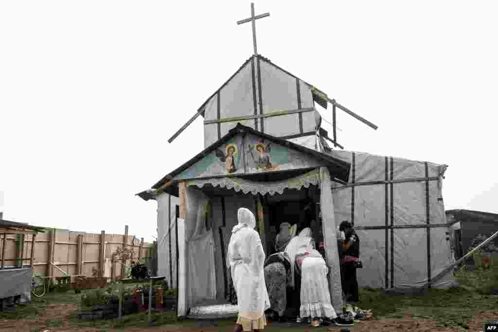 Migran Kristen Koptik Ethiopia tiba untuk melakukan misa di gereja Orthodox darurat di kamp "Jungle" di kota Calais, Perancis utara.