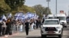 Israelis wave the national flag as the convoy of vehicles transporting the bodies of the four Israeli hostages handed over by Hamas, arrives at the entrance to the National Center of Forensic Medicine in Tel Aviv, Feb. 20, 2025.
