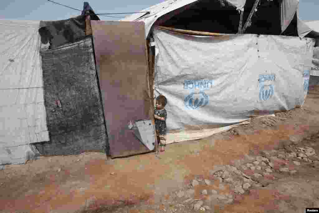 A child stands outside her family's tent near the site of a bomb attack in Jalozai camp in Nowshera district, northwestern Pakistan, March 21, 2013.