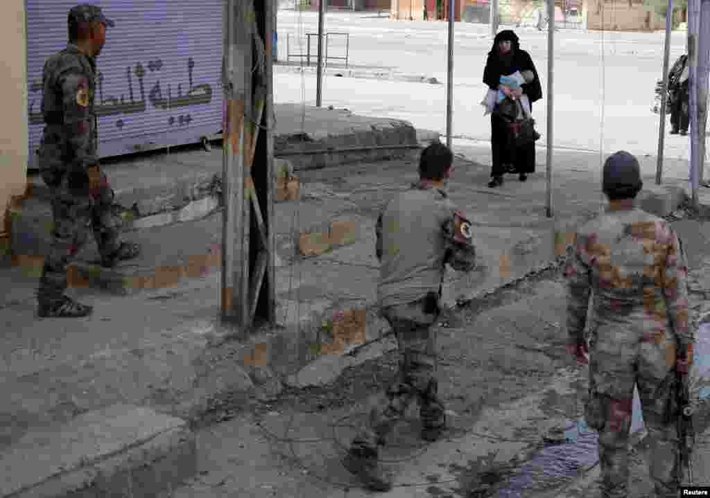 Seorang perempuan menggendong bayinya saat mengungsi dari daerah yang dikuasai ISIS di kota Mosul ke daerah yang dikuasai pasukan Irak.