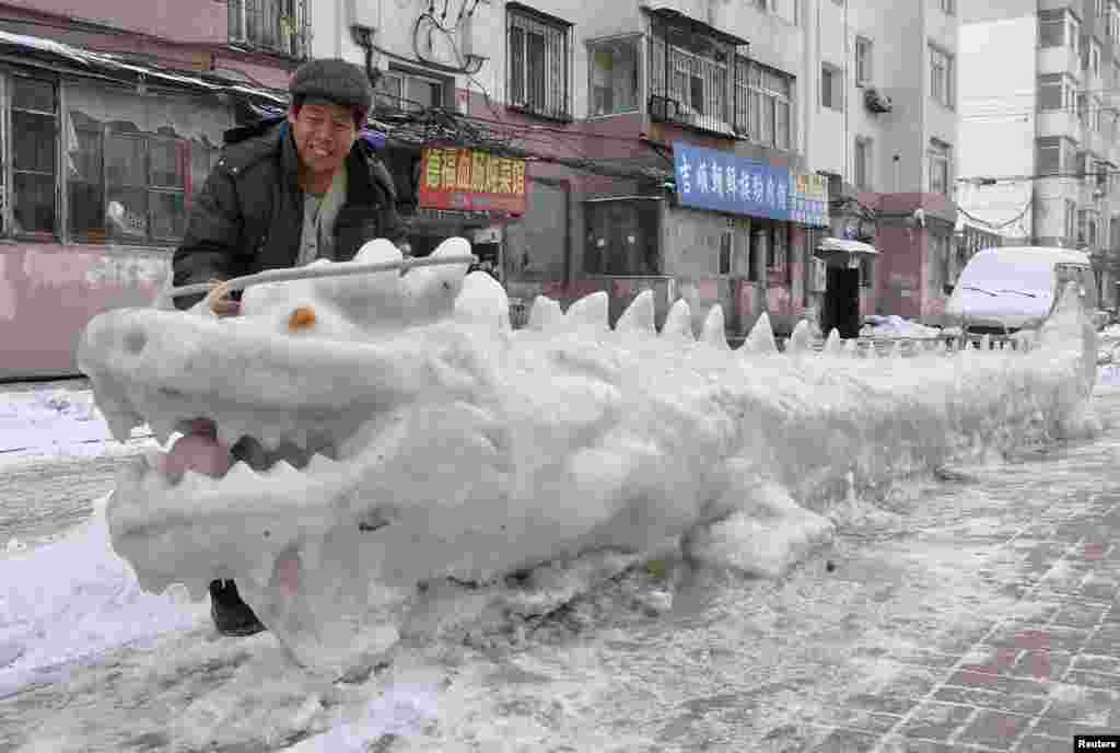 Seorang pria melihat patung &quot;dragon&quot; yang dibuat dari salju oleh warga setempat di kota Jilin, provinsi Jilin, China.