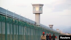 资料图片：几名工人在新疆一再教育营外走过。