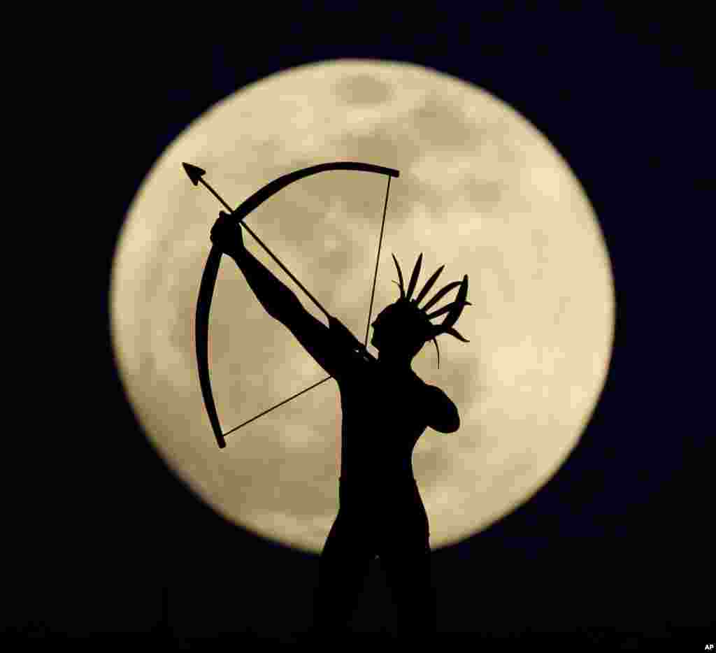 Bulan purnama tampak di belakang patung pahlawan suku Indian-Kansas di kota Topeka, Kansas, Amerika.